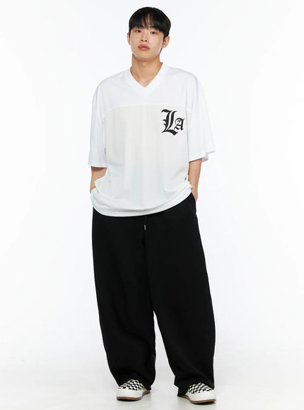 Men's Oversized Mesh Rugby Tee IL514 White front full-body shot on male model with hands in pockets, black La gothic chest logo, styled with wide-leg black pants and checkered sneakers