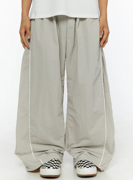 LEWKIN Men's Oversized Sweatpants IL510 Light gray front close-up on model showing wide-leg silhouette, white piping detail, and drawstring waist, nylon fabric