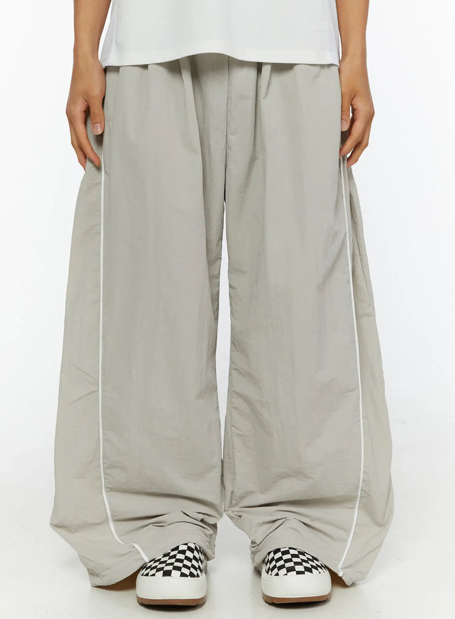 LEWKIN Men's Oversized Sweatpants IL510 Light gray front close-up on model showing wide-leg silhouette, white piping detail, and drawstring waist, nylon fabric