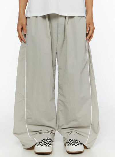 LEWKIN Men's Oversized Sweatpants IL510 Light gray front close-up on model showing wide-leg silhouette, white piping detail, and drawstring waist, nylon fabric
