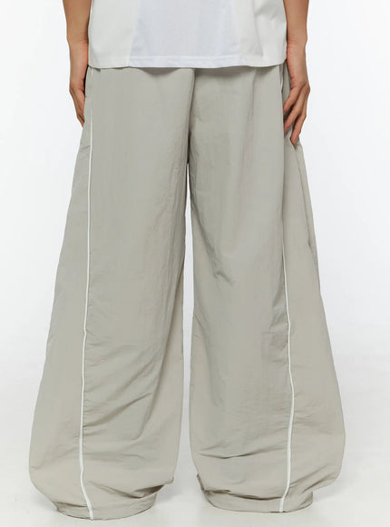Men's Oversized Sweatpants IL510 Light gray back view on model showing wide-leg silhouette, white side piping, and elasticated waistband with nylon fabric