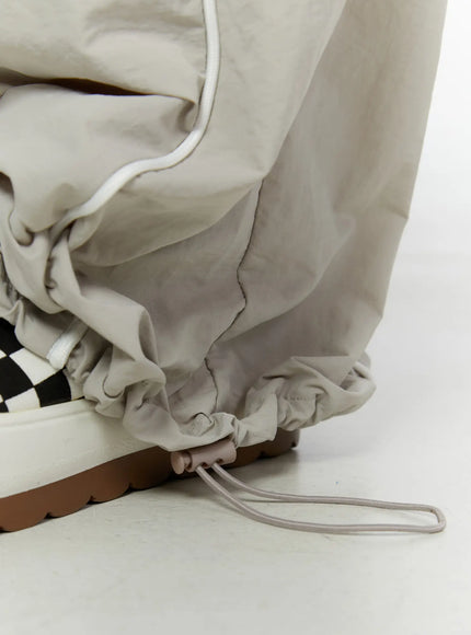 Men's Oversized Sweatpants IL510 Light gray close-up detail of hem drawstring toggle and gathered ankle cuff with white piping on nylon fabric