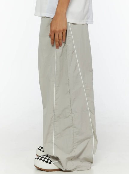 Men's Oversized Sweatpants IL510 Light gray side view on model highlighting white contrast piping seam running full length of wide-leg nylon pant