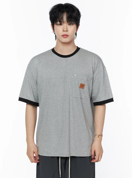Men's Patch Detail Short Sleeve Tee IU523 Gray close-up front view on male model, heathered gray cotton fabric, black ringer crewneck and cuffs, chest pocket with square leather brand patch