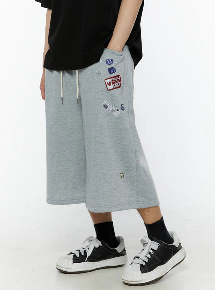 Men's Patch Detail Shorts (Gray) IL509 gray close-up side shot on model highlighting Fragile sticker and barcode patches near drawstring waistband