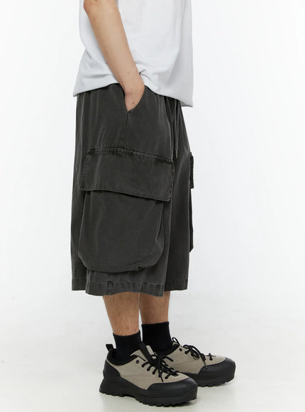 Men's Pigment Bermuda Cargo Shorts (Dark Gray) IL507 Dark gray right side model shot hand in pocket showing cargo pocket elastic waistband and relaxed wide-leg fit