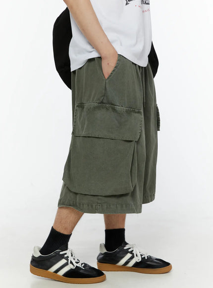 LEWKIN Men's Pigment Bermuda Cargo Shorts (Dark Green) IL507 Dark green side view on male model hand in pocket paired with white graphic tee and sneakers