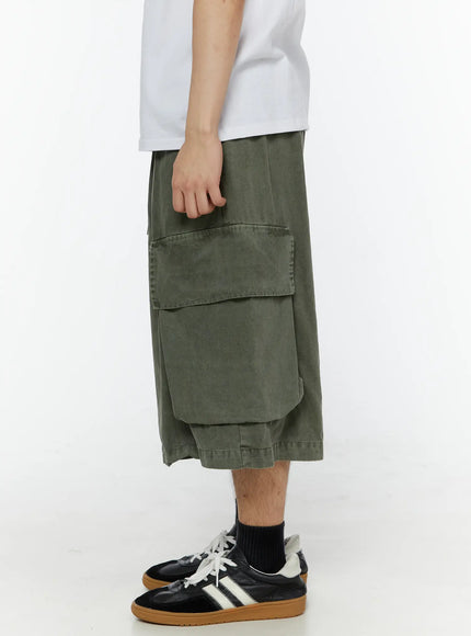 Men's Pigment Bermuda Cargo Shorts (Dark Green) IL507 Dark green right side view on male model highlighting oversized flap cargo pocket and elastic drawstring waistband