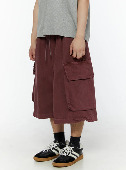 Men's Pigment Bermuda Cargo Shorts (Dark Pink) IL507 Dark Pink side view on model showing large flap cargo pocket and layered hem detail, styled with gray tee