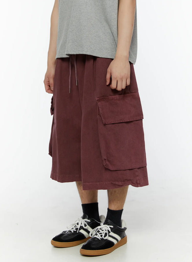 Men's Pigment Bermuda Cargo Shorts (Dark Pink) IL507 Dark Pink side view on model showing large flap cargo pocket and layered hem detail, styled with gray tee