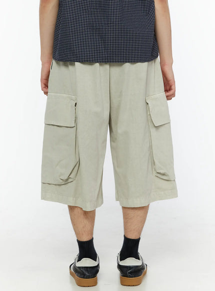 Men's Pigment Bermuda Cargo Shorts (Light Beige) IL507 Light Beige back shot on male model showing rear cargo pockets and wide-leg bermuda length with sneakers