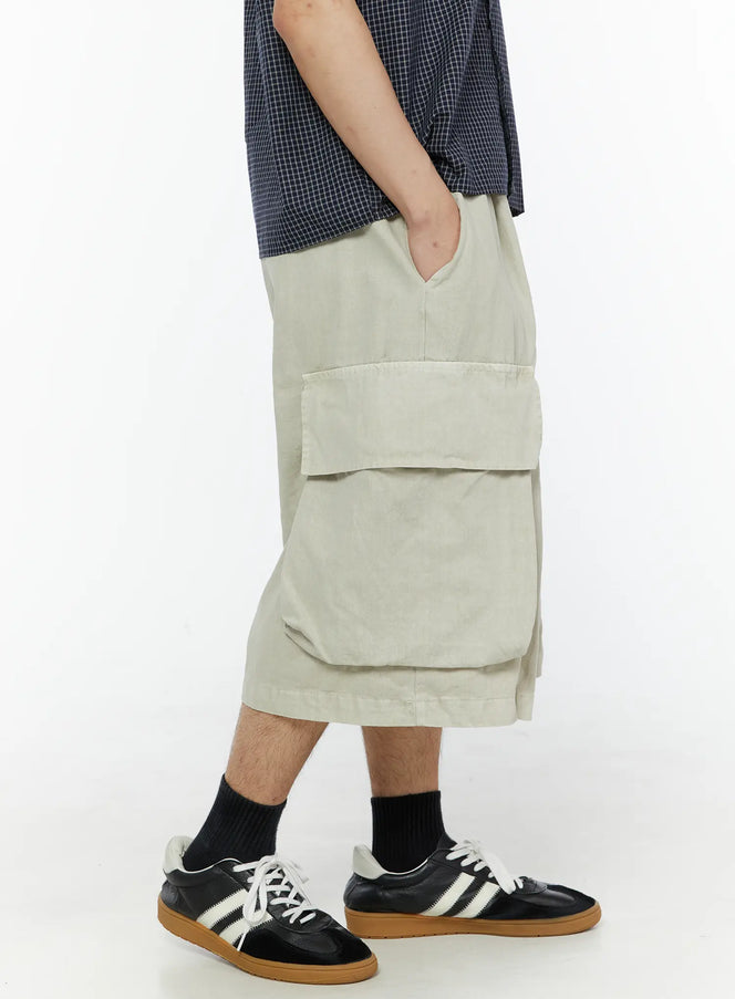 Men's Pigment Bermuda Cargo Shorts (Light Beige) IL507 Light Beige side shot on male model showing large flap cargo pocket profile with hand resting on thigh