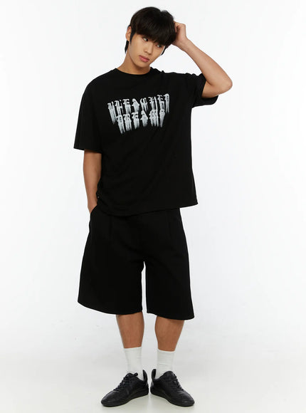 Men's Pintuck Bermuda Shorts IL515 Black full-body front shot on male model with hand on head, styled with graphic tee and black sneakers