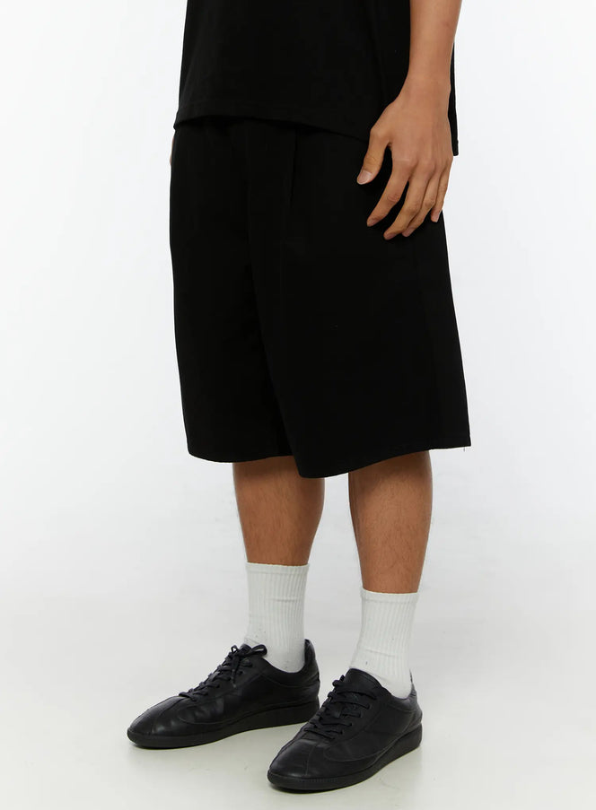 Men's Pintuck Bermuda Shorts IL515 Black side close-up on male model showing wide-leg hem, pintuck detail, and black sneakers with white socks