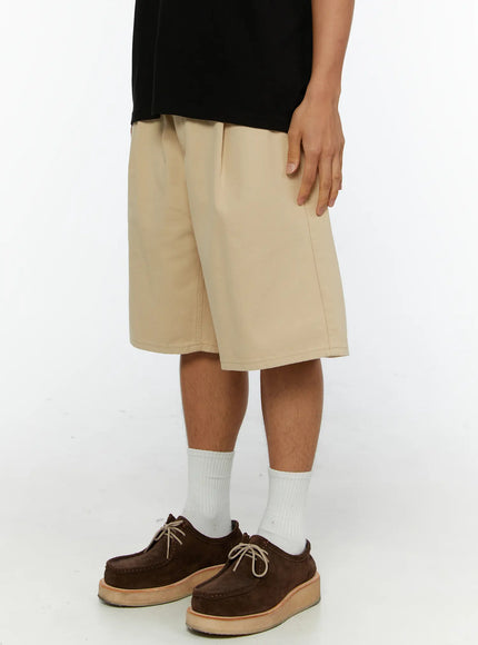 Men's Pintuck Cotton Bermuda Shorts IL515 Beige side view on model showing pintuck pleat detail wide leg cut and knee-length hem with cotton fabric texture