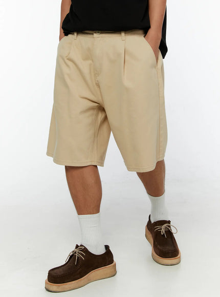 Men's Pintuck Cotton Bermuda Shorts IL515 Beige front view on model with hands in pockets wearing black tee styled with white socks and brown suede shoes