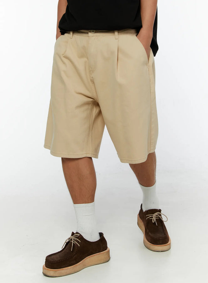 Men's Pintuck Cotton Bermuda Shorts IL515 Beige front view on model with hands in pockets wearing black tee styled with white socks and brown suede shoes
