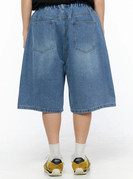 Men's Pintuck Jorts IL510 Blue back view on model showing dual patch pockets, elastic waistband, and washed denim finish with yellow sneakers