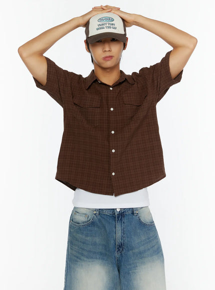 Men's Plaid Button-Up Shirt IL513 Brown front shot on model with arms raised overhead wearing cap, showing dual chest pockets and cropped hem