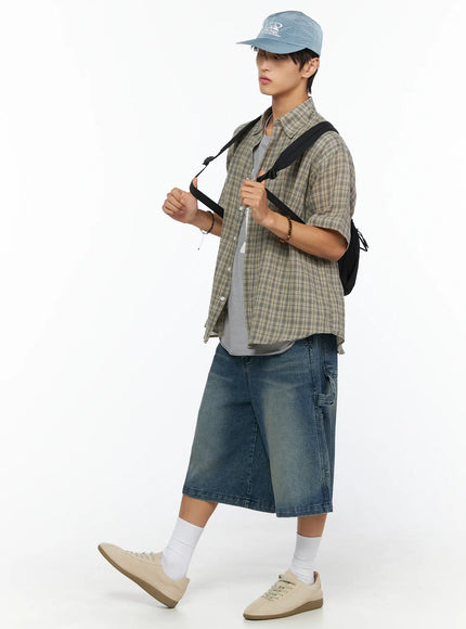 Men's Plaid Button-Up Shirt IL520 khaki green side walking shot on male model, open plaid shirt with backpack strap, cap, denim shorts and sneakers, casual look