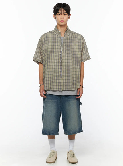 Men's Plaid Button-Up Shirt IL520 khaki green front full-body shot on male model, oversized plaid short-sleeve shirt styled with denim shorts and sneakers