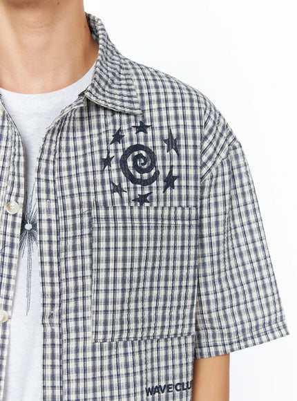 Men's Plaid Graphic Button-Up Shirt IL528 light beige close-up front detail shot on model showing SPIRAL DoNe graphic and seersucker plaid texture with pearl buttons