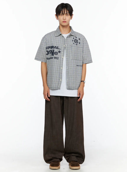 Men's Plaid Graphic Button-Up Shirt IL528 light beige front full-body shot on male model standing straight showing spiral star and SPIRAL DoNe graphic embroidery