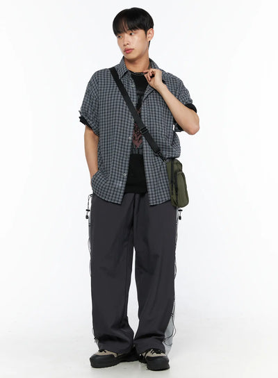 LEWKIN Men's Plaid Roll-Up Short Sleeve Shirt IL514 Gray M/L full-body styled shot on model posed at angle with crossbody bag layered over graphic tee and wide-leg pants