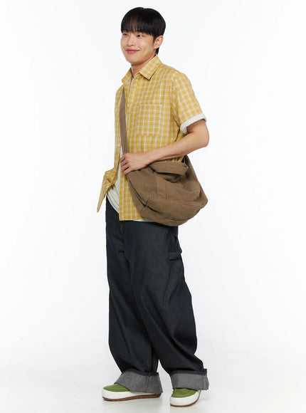 Men's Plaid Short Sleeve Shirt IL510 Yellow three-quarter side shot on model smiling carrying brown canvas messenger bag with wide-leg denim