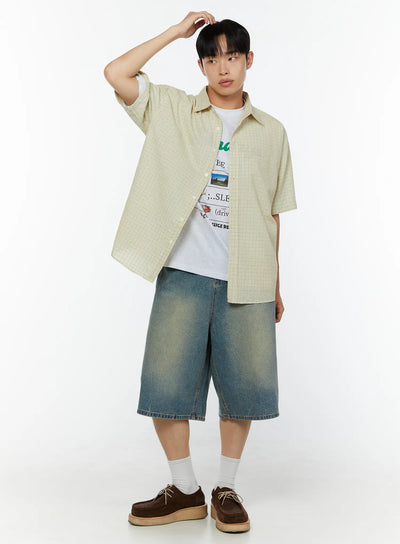 LEWKIN Men's Plaid Short Sleeve Shirt IU529 Light yellow full-body angled shot on male model hand raised to head layered over graphic tee with denim shorts