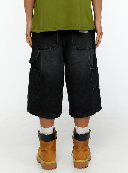 Men's Relaxed Denim Carpenter Shorts IL513 Black back view on model, showing dual back pockets and side cargo pockets, paired with olive tee and tan boots