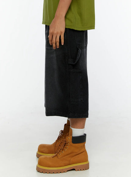 Men's Relaxed Denim Carpenter Shorts IL513 Black side view on model, showing wide-leg silhouette and cargo pocket depth, paired with olive tee and tan boots