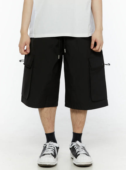 Men's Relaxed Fit Cargo Shorts (Black) IL509 black front close-up shot on model showing dual cargo pockets with drawstring toggles and elastic waistband