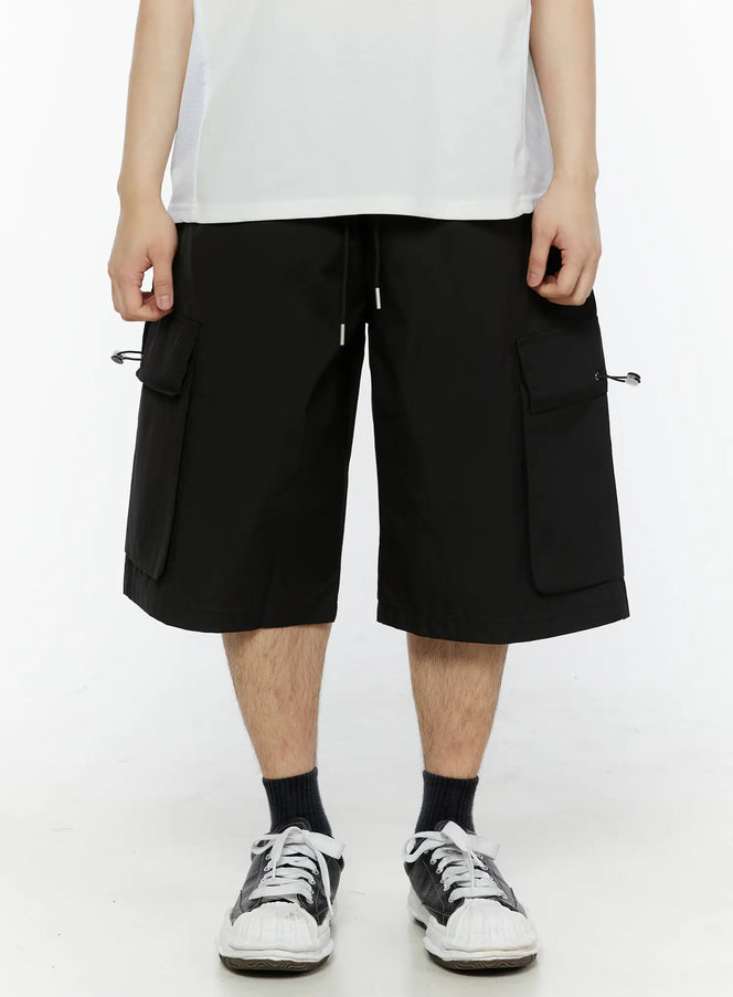 Men's Relaxed Fit Cargo Shorts (Black) IL509 black front close-up shot on model showing dual cargo pockets with drawstring toggles and elastic waistband