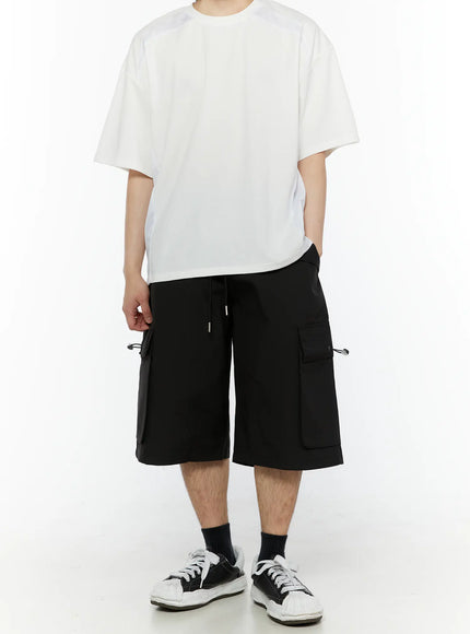 Men's Relaxed Fit Cargo Shorts (Black) IL509 black full front shot on model styled with oversized white tee and sneakers showing wide-leg silhouette