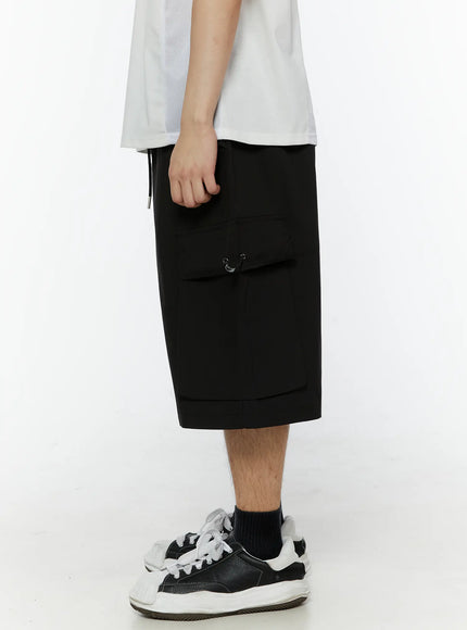 Men's Relaxed Fit Cargo Shorts (Black) IL509 black side shot on model highlighting large flap cargo pocket with metal clip closure and hem band