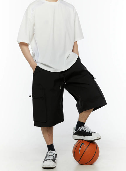 LEWKIN Men's Relaxed Fit Cargo Shorts (Black) IL509 black styled shot model posing with foot on basketball wearing white tee