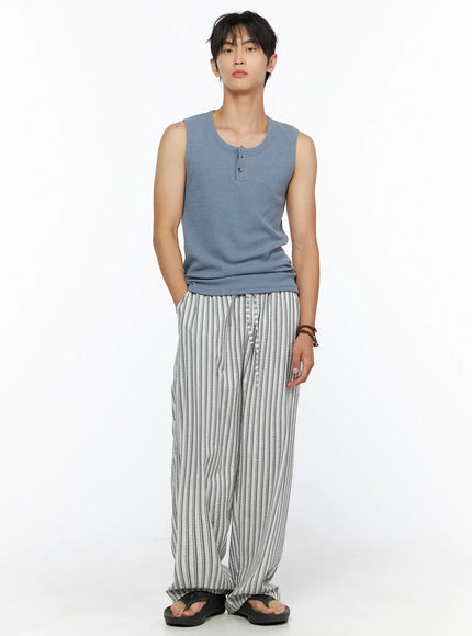 Men's Relaxed-Fit Pajama Pants IL520 Dark blue full front shot on male model standing straight wearing wide-leg striped pants with blue waffle tank top and black flip flops