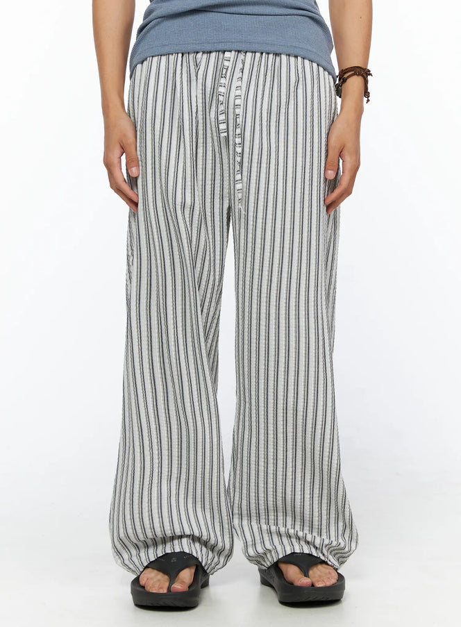 LEWKIN Men's Relaxed-Fit Pajama Pants IL520 Dark blue front close-up on model wearing wide-leg seersucker stripe trousers with button fly and elastic waist styled with sandals