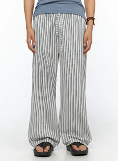 LEWKIN Men's Relaxed-Fit Pajama Pants IL520 Dark blue front close-up on model wearing wide-leg seersucker stripe trousers with button fly and elastic waist styled with sandals