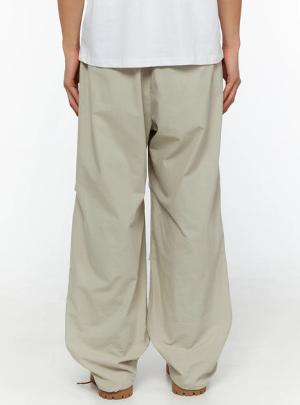 Men's Relaxed-Fit Parachute Pants IL509 Light beige back view on model showing wide relaxed fit rear panel and ruched hem with tan boots