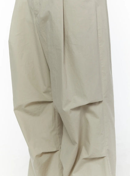 Men's Relaxed-Fit Parachute Pants IL509 Light beige close-up detail shot showing crinkled parachute nylon fabric texture and voluminous thigh area