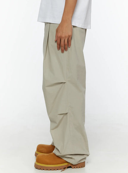 Men's Relaxed-Fit Parachute Pants IL509 Light beige side shot on model showing straight side seam and oversized wide-leg nylon drape with tan boots