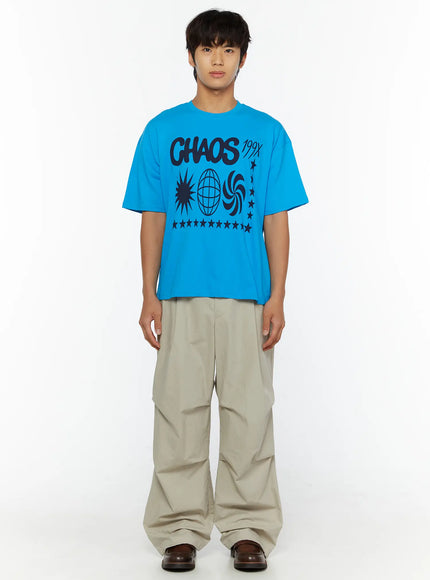 Men's Relaxed-Fit Parachute Pants IL509 Light beige full-body front shot on model in blue graphic tee arms relaxed showing wide parachute leg silhouette