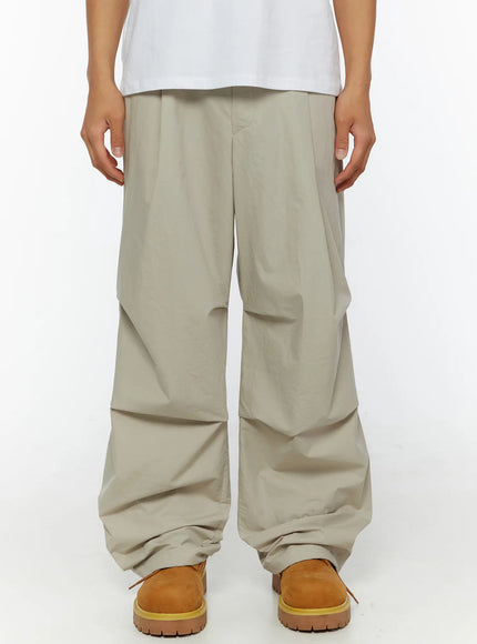 LEWKIN Men's Relaxed-Fit Parachute Pants IL509 Light beige front close-up on model showing wide-leg silhouette and draped nylon fabric with tan boots