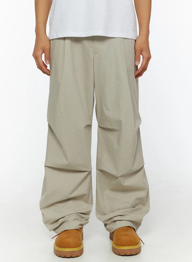 LEWKIN Men's Relaxed-Fit Parachute Pants IL509 Light beige front close-up on model showing wide-leg silhouette and draped nylon fabric with tan boots
