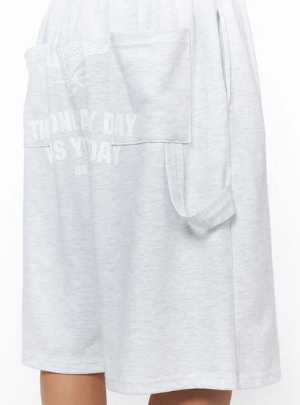 Men's Relaxed-Fit Sweat Shorts IL515 Light gray close-up detail of side cargo pocket and tonal eagle graphic print on heathered fleece fabric