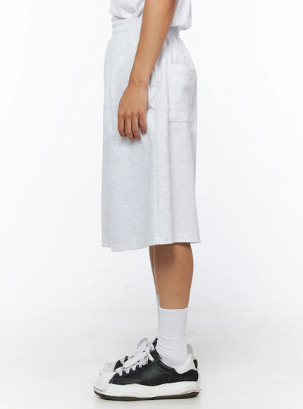 Men's Relaxed-Fit Sweat Shorts IL515 Light gray side profile view on model showing clean side seam, knee-length hem and heathered cotton fleece texture with sneakers