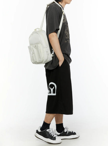 Men's Shooting Star Printed Shorts (Black) IL509 side view on male model carrying white backpack, showing full length and white arch figure graphic on leg