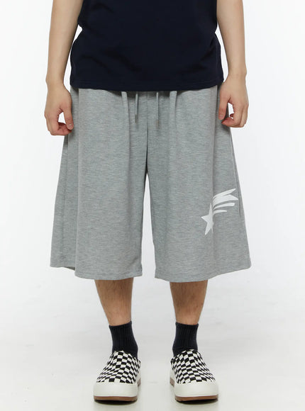 LEWKIN Men's Shooting Star Printed Shorts (Gray) IL509 Gray M/L front view on model with wide-leg silhouette, drawstring waist, and white shooting star print, styled with navy tee and checkered slip-ons